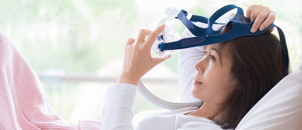 Woman putting on CPAP mask ,sleep apnea therapy