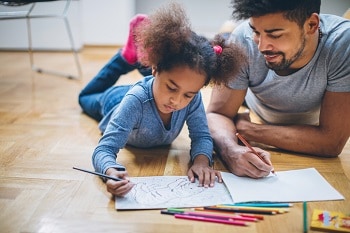 Father and daughter drawing indoors