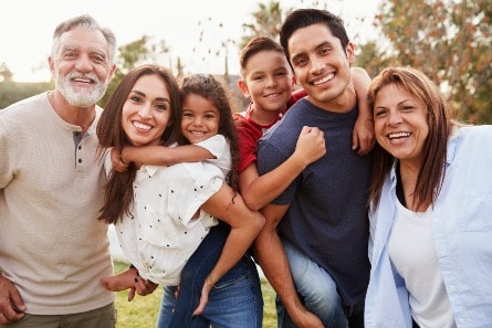 Three generation Hispanic family standing in the park.