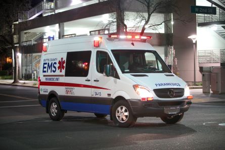 ambulance with sirens on a city street at night